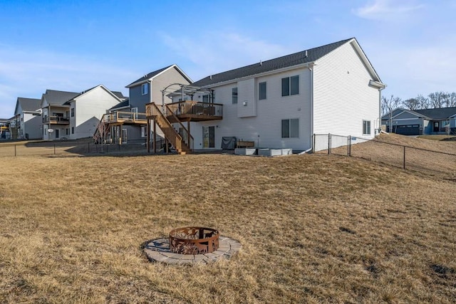 rear view of property featuring an outdoor fire pit, a lawn, stairs, fence, and a wooden deck