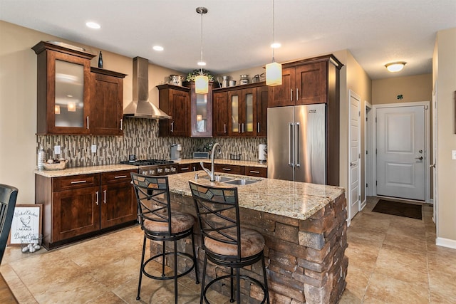 kitchen featuring backsplash, wall chimney exhaust hood, stainless steel appliances, and a sink