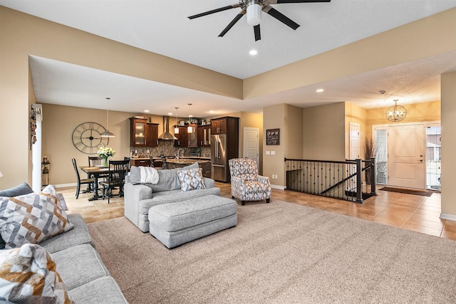 living area featuring ceiling fan with notable chandelier, recessed lighting, baseboards, and light tile patterned floors