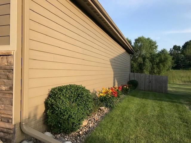 view of side of home with fence and a yard