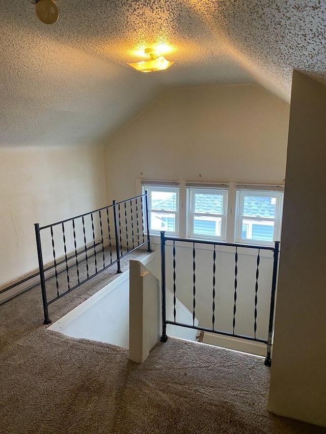 bonus room featuring carpet floors, plenty of natural light, vaulted ceiling, and a textured ceiling