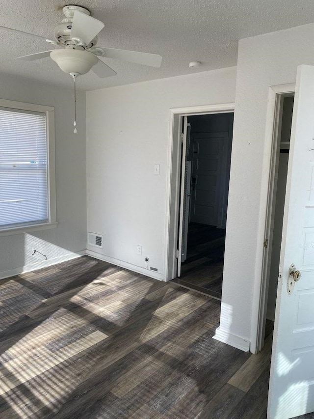 unfurnished bedroom featuring baseboards, visible vents, a ceiling fan, wood finished floors, and a textured ceiling