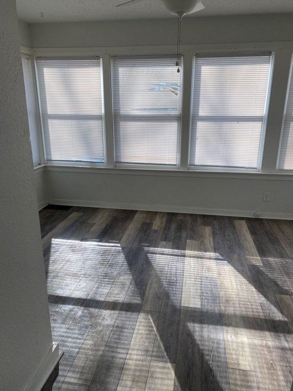 spare room with a textured wall, a textured ceiling, and wood finished floors