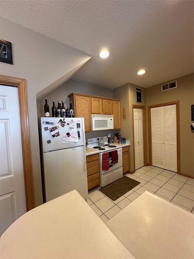 kitchen with light tile patterned floors, light countertops, visible vents, a textured ceiling, and white appliances