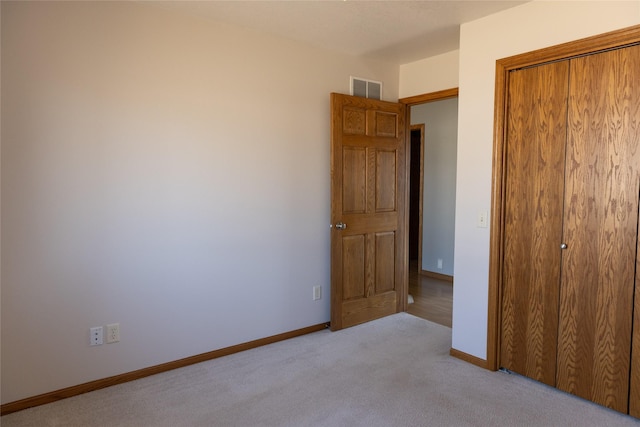 unfurnished bedroom with light carpet, baseboards, visible vents, and a closet