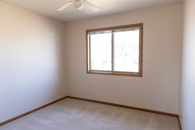 empty room featuring baseboards, visible vents, ceiling fan, and light colored carpet