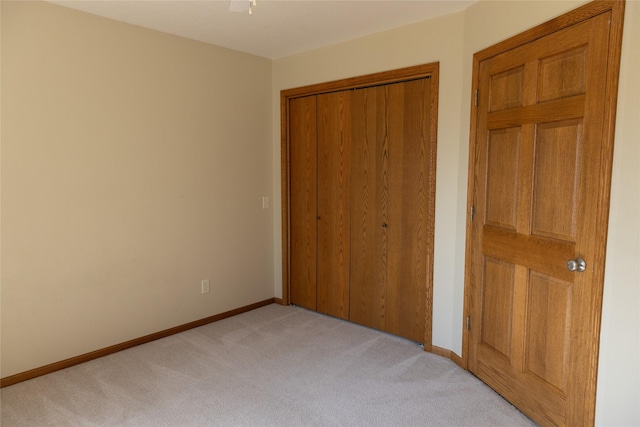 unfurnished bedroom featuring a closet, light colored carpet, and baseboards