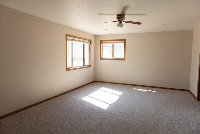 carpeted spare room featuring ceiling fan and baseboards