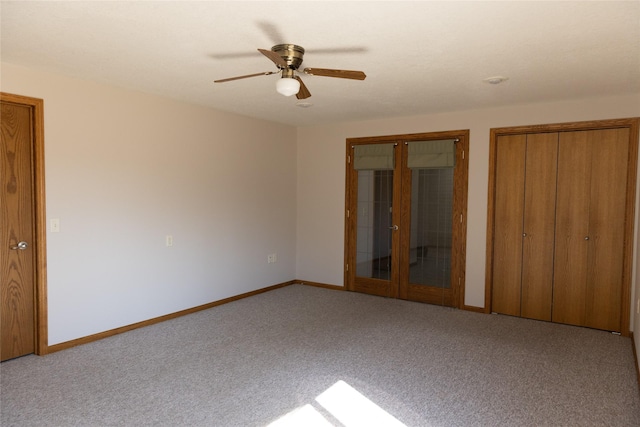 unfurnished bedroom with multiple closets, carpet, french doors, and baseboards