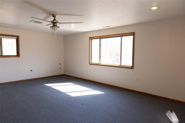 carpeted spare room featuring a ceiling fan, visible vents, and baseboards