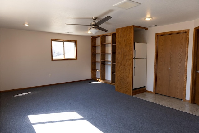 spare room featuring light carpet, light tile patterned floors, baseboards, and visible vents