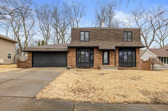 view of front of home with driveway, an attached garage, a shingled roof, and brick siding