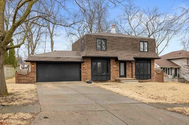 view of front of property with driveway, a shingled roof, a chimney, an attached garage, and brick siding