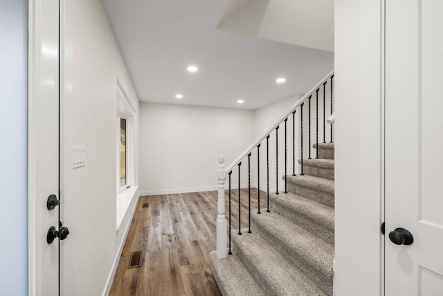 stairway featuring baseboards, wood finished floors, visible vents, and recessed lighting