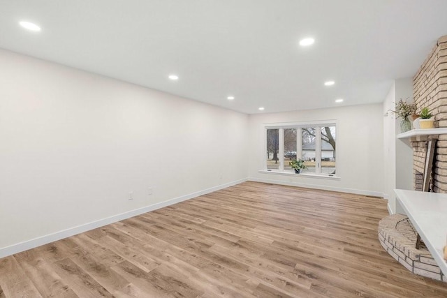 unfurnished living room with recessed lighting, baseboards, light wood-style floors, and a fireplace