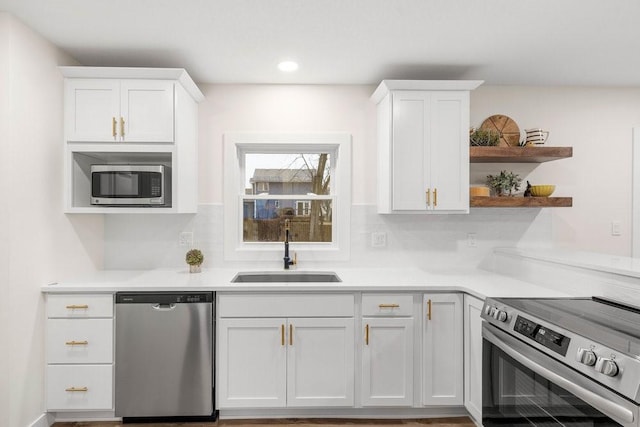 kitchen with a sink, white cabinetry, open shelves, light countertops, and appliances with stainless steel finishes