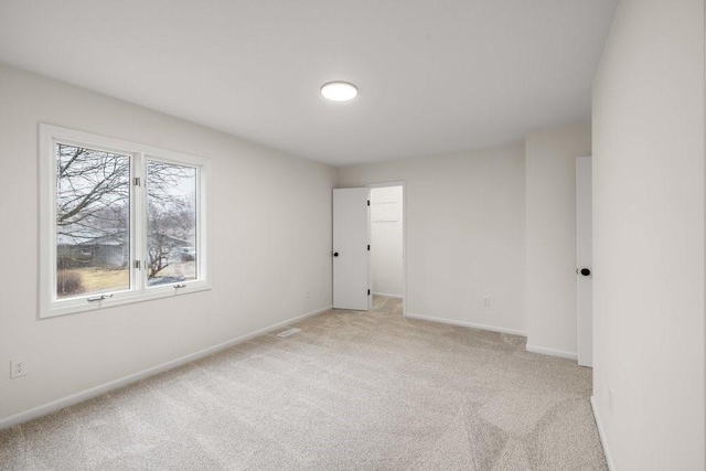 unfurnished room with light colored carpet, baseboards, and visible vents