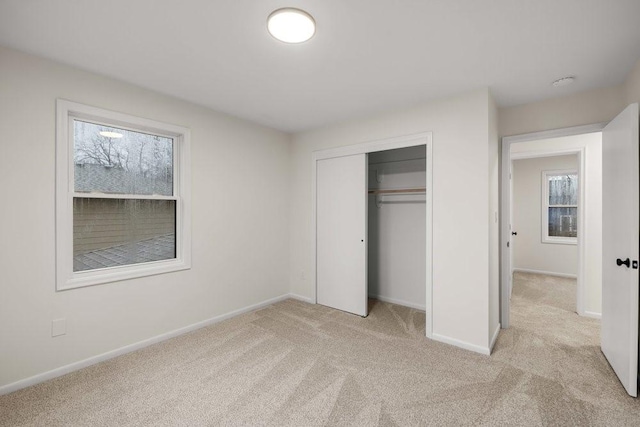 unfurnished bedroom with a closet, baseboards, and light carpet