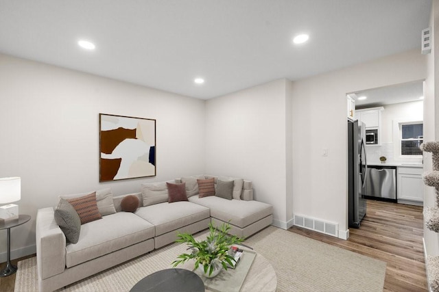 living room featuring recessed lighting, wood finished floors, visible vents, and baseboards