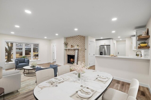 dining room with light wood finished floors, baseboards, a fireplace, and recessed lighting