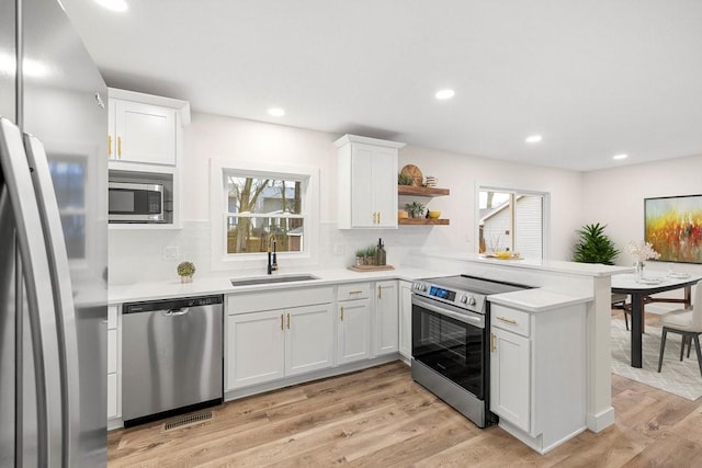 kitchen with a peninsula, light countertops, a sink, and appliances with stainless steel finishes