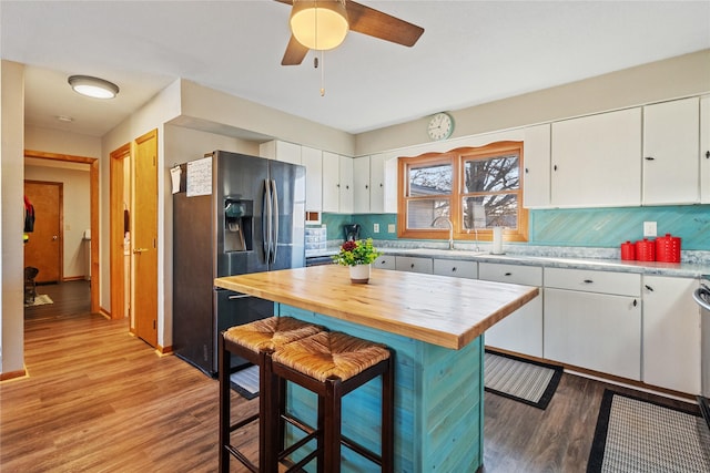 kitchen with white cabinets, light wood-type flooring, stainless steel refrigerator with ice dispenser, and wooden counters