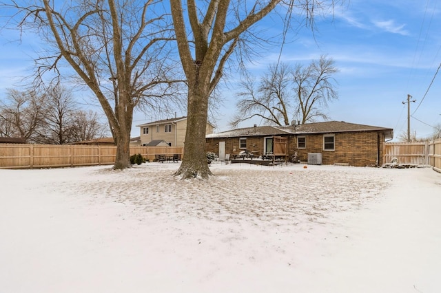 snow covered house featuring a fenced backyard