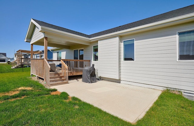 rear view of property with a deck, a yard, and a patio area