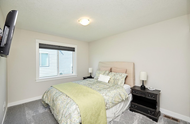 carpeted bedroom with a textured ceiling, visible vents, and baseboards