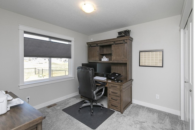 home office with light carpet, visible vents, baseboards, and a textured ceiling