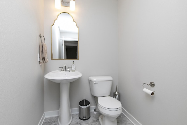 half bathroom featuring baseboards and toilet