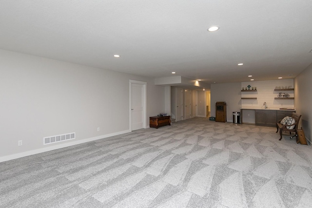 unfurnished living room featuring recessed lighting, wet bar, visible vents, and light colored carpet