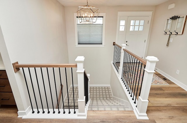 stairs featuring a notable chandelier, baseboards, and wood finished floors