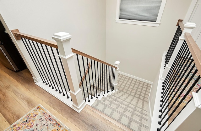 staircase featuring baseboards and wood finished floors