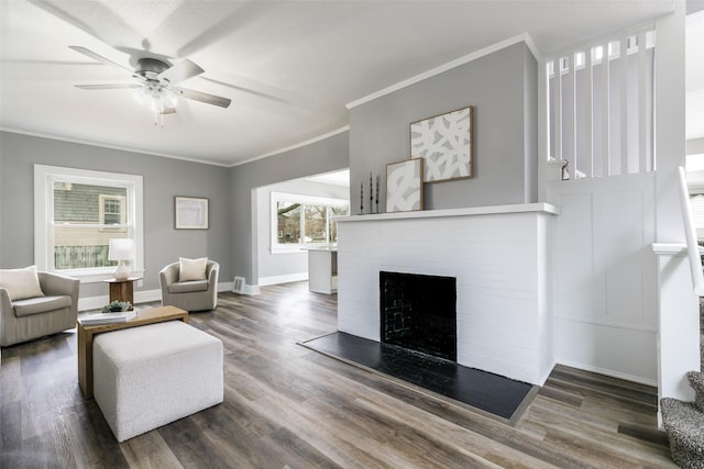 living room with ornamental molding, a fireplace, baseboards, and wood finished floors