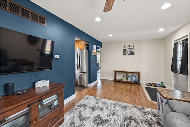 living area with light wood-style floors, baseboards, visible vents, and recessed lighting