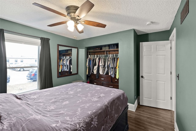 bedroom with dark wood finished floors, a closet, visible vents, a textured ceiling, and baseboards