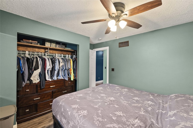 bedroom featuring visible vents, a ceiling fan, wood finished floors, a textured ceiling, and a closet