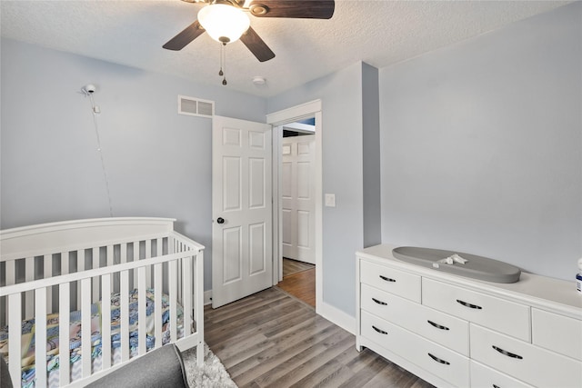 bedroom with light wood-style flooring, visible vents, ceiling fan, and a textured ceiling