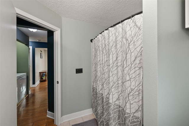 full bath featuring a textured ceiling, wood finished floors, and baseboards