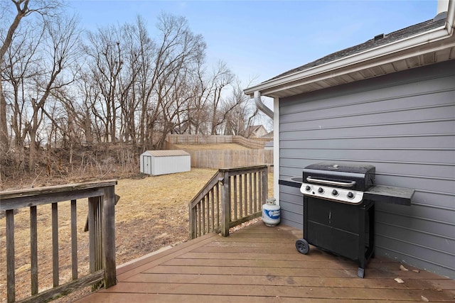 wooden terrace featuring an outbuilding, a grill, fence, and a shed