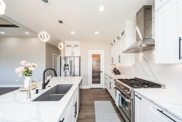 kitchen with dark wood finished floors, high end appliances, wall chimney exhaust hood, white cabinetry, and a sink