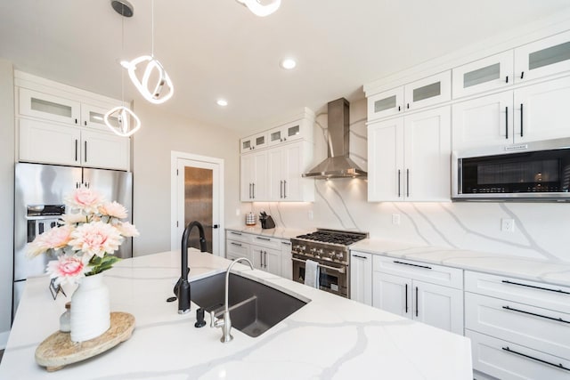 kitchen with tasteful backsplash, hanging light fixtures, stainless steel appliances, wall chimney range hood, and white cabinetry