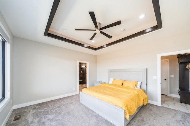 carpeted bedroom featuring visible vents, baseboards, ensuite bathroom, a tray ceiling, and recessed lighting