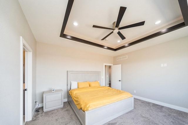 bedroom with baseboards, visible vents, a raised ceiling, and light colored carpet