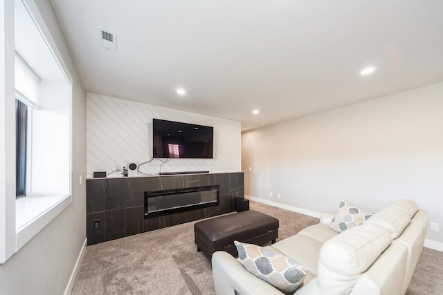 carpeted living room with a glass covered fireplace, visible vents, baseboards, and recessed lighting