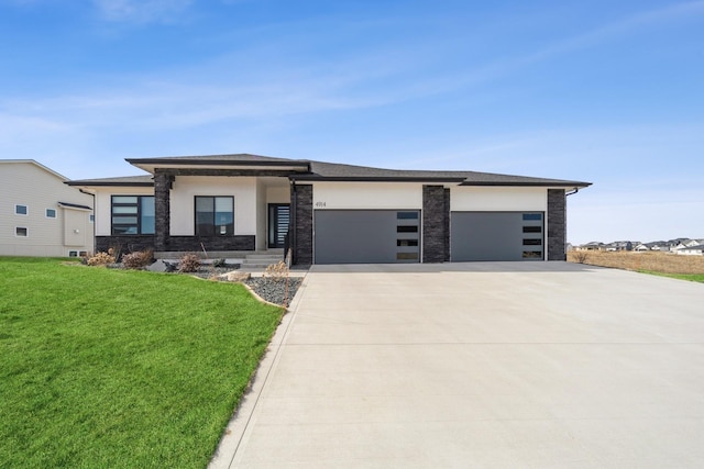 prairie-style house featuring a garage, concrete driveway, a front lawn, and stucco siding