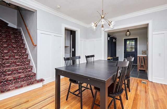 dining area with stairs, ornamental molding, visible vents, and a decorative wall