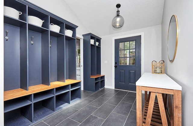 mudroom with lofted ceiling, a textured ceiling, and dark tile patterned floors