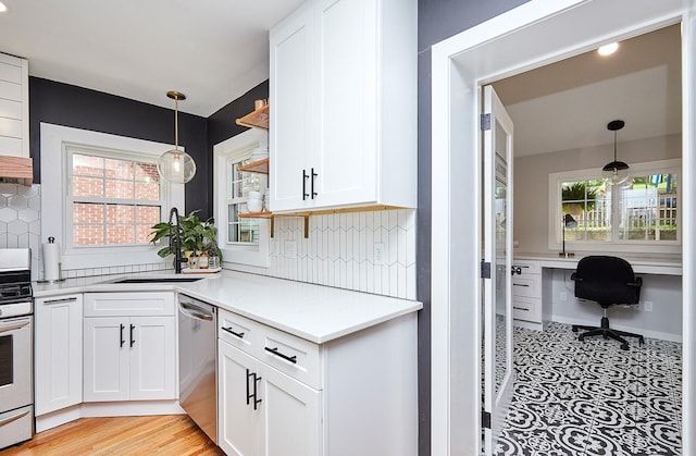 kitchen featuring stainless steel appliances, a sink, white cabinetry, light countertops, and open shelves